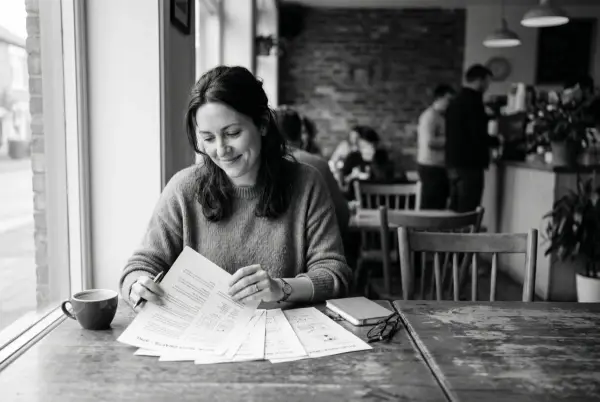 Un empresario sentado relajado en un café lee borradores de redes sociales, fotografía en blanco y negro